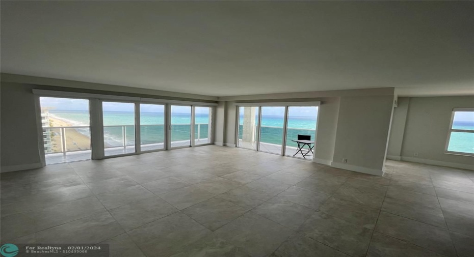 The large living room with marble tile and floor-to-ceiling impact windows and doors.
