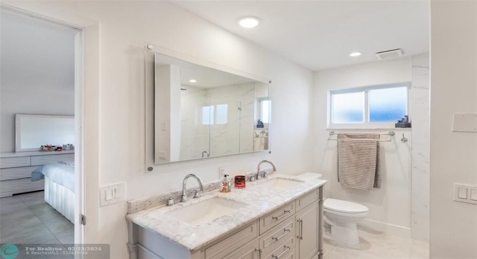 Dual marble sinks and large step in shower with glass door
