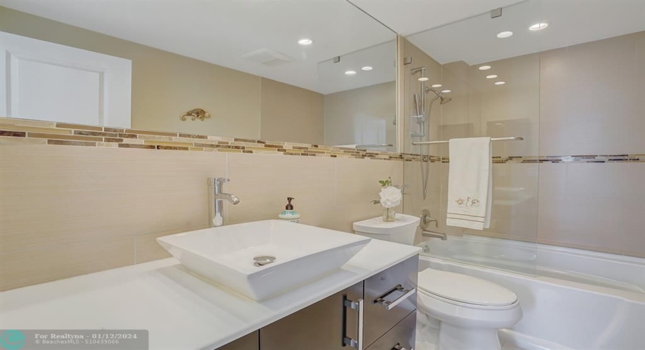 Beautifully redone bath with mosaic accent, glass bath enclosure and designer lighting.