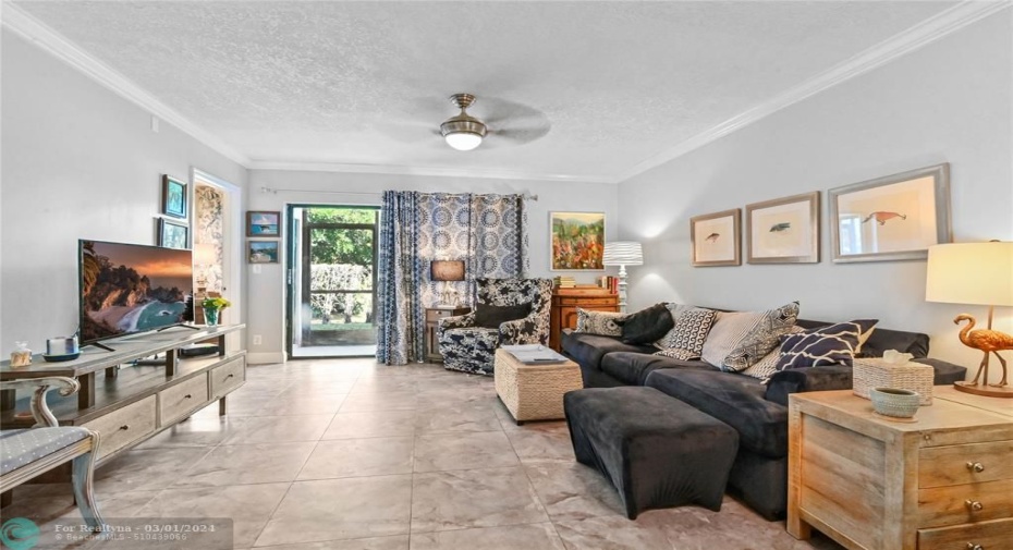 Spacious living room with designer ceiling fan and sliding glass doors to screened patio