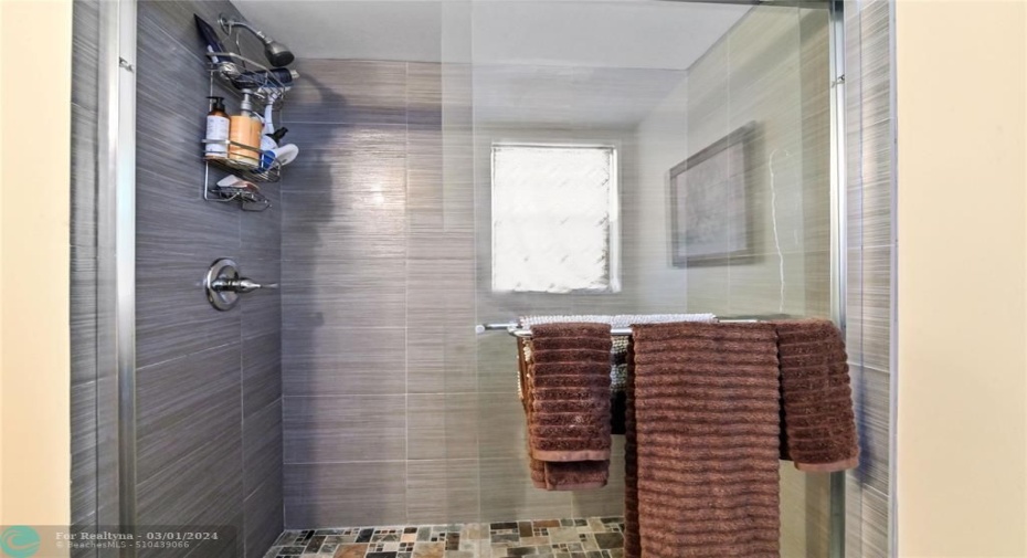 Primary bath has designer shower with frameless glass shower doors