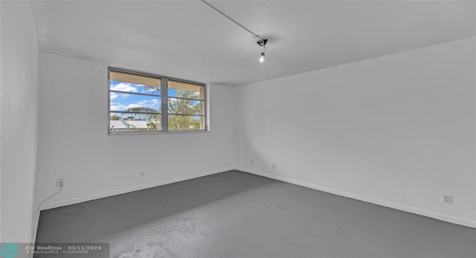 Bedroom #1 with concrete flooring and overhead lighting