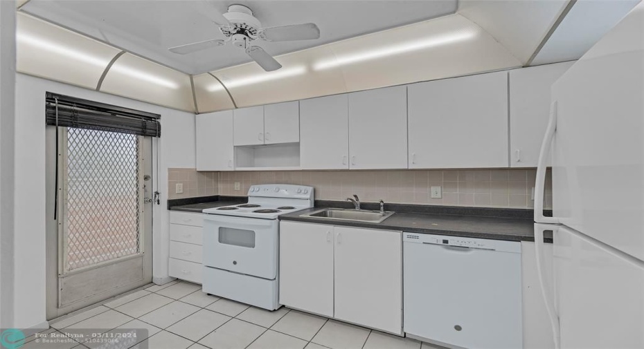 White and bright kitchen offers great cabinet and storage space and a door entering into kitchen