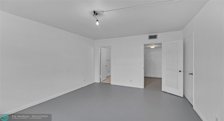 Master bedroom with walk in closet and concrete floorfing