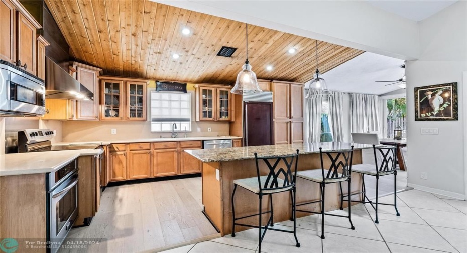 Kitchen with wood cabinetry, center Island, two ovens, range rood, subzero refrigerator and lots of storage.