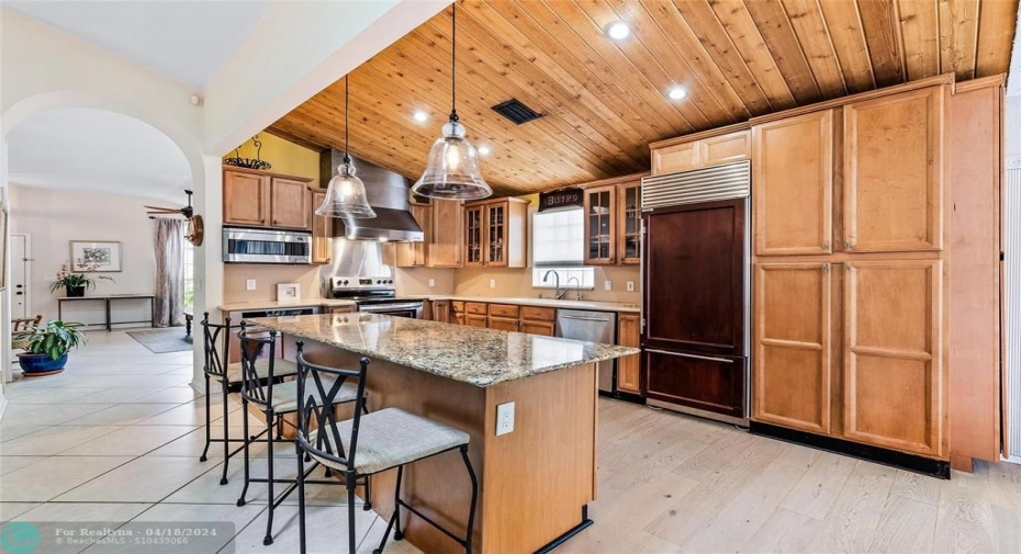 Kitchen with wood cabinetry, center Island, two ovens, range rood, subzero refrigerator and lots of storage.