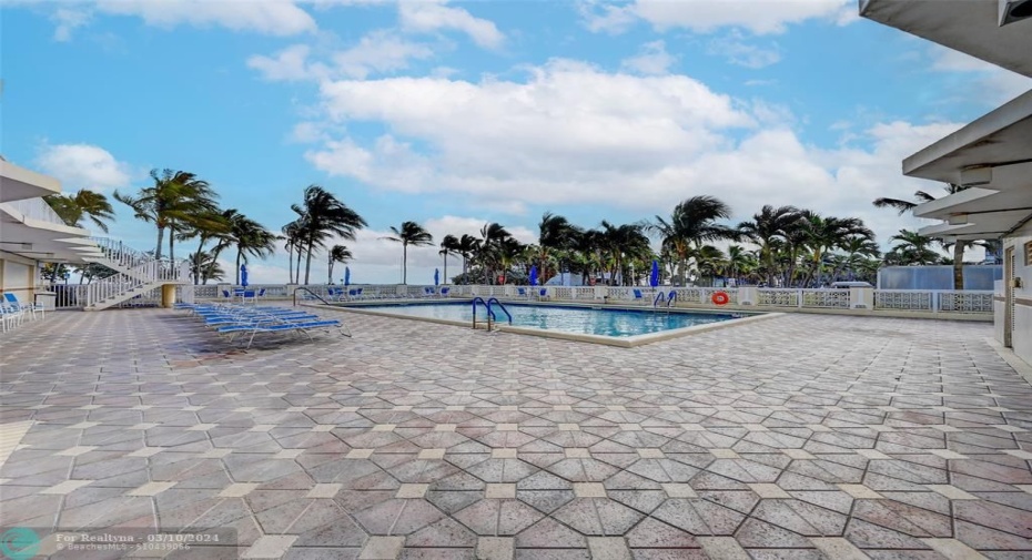Pool deck with luxe lounge chairs, tables, chairs and umbrellas