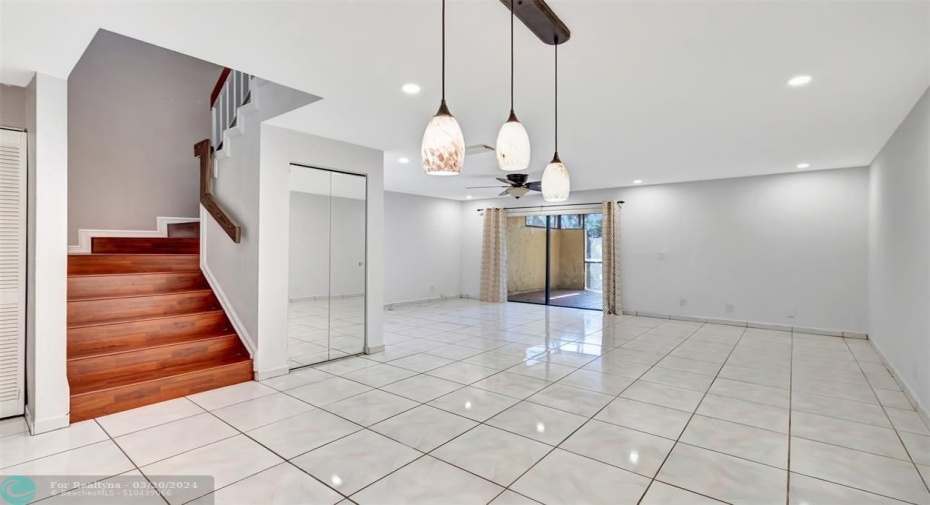 Lovely white tile dining and living room with laminate wood stairs.  storage closet under stairs, all high hat lighting and freshly painted