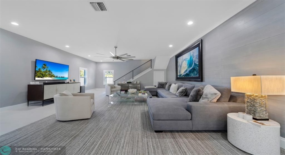 Oversized Living room with elegant and deep sectional, wall mounted smart TV, hurricane impact windows with plantation shutters to create dark or light at your finger tips.
