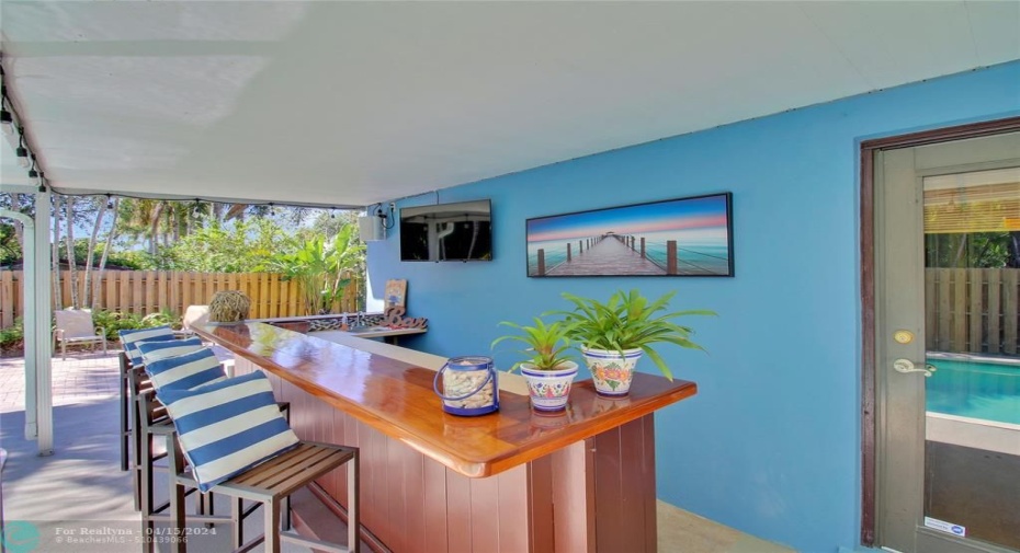 Custom teak hard wood Bar with mini fridge, exterior speakers and tv.  Great place for game watching and pool side fun!