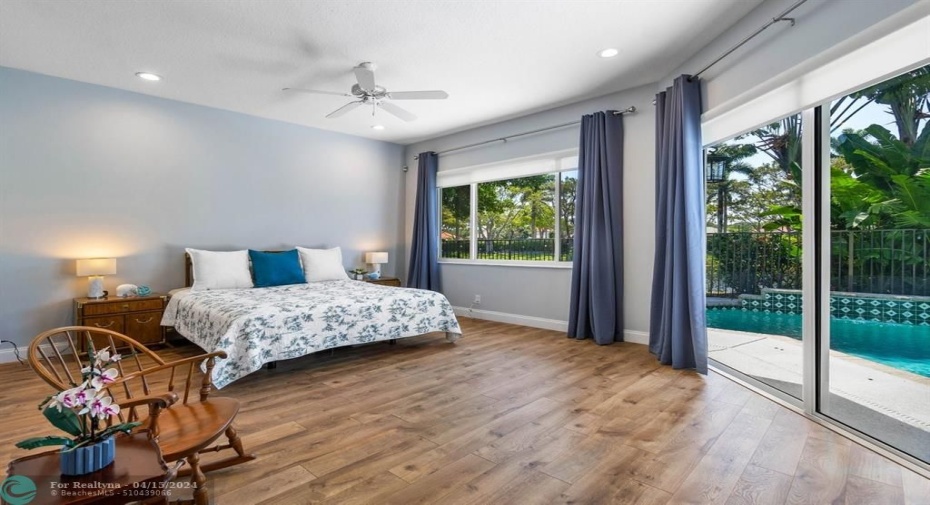 Primary bedroom boasts luxury vinyl flooring  and beautiful pool, patio and water views.