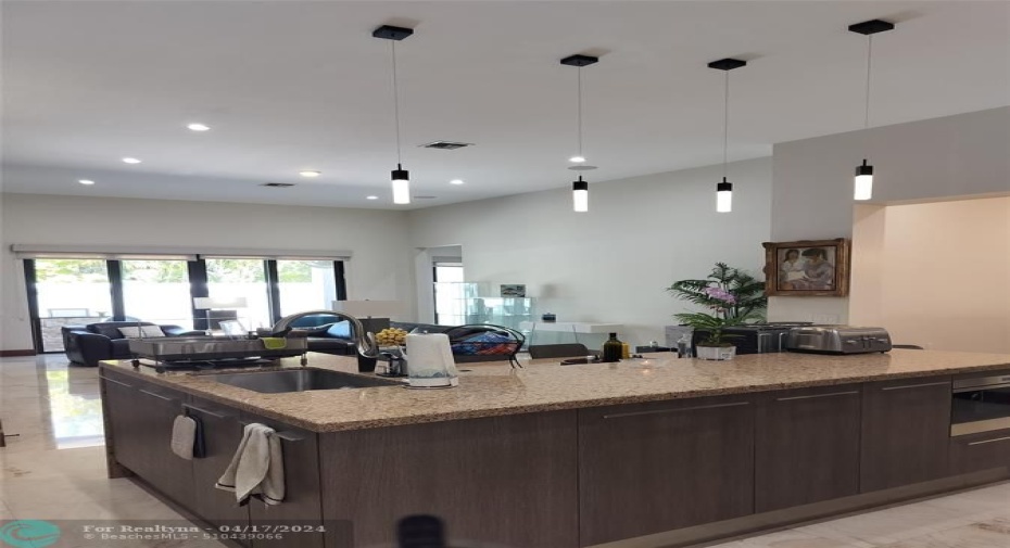 Island with double sink and cabinetry storage under over looks to the family room