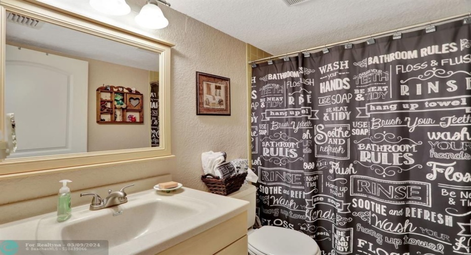 GUEST BATH WITH NEUTRAL COLOR TILE IN TUB SHOWER COMBINATION. VANITY, MIRROR, LIGHT FIXTURE AND COMMODE REPLACED