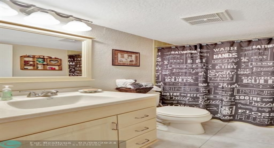 GUEST BATHROOM. FLOOR TILE REPLACED. VANITY LIGHT FIXTURE AND MIRROR REPLACED. NEUTRAL COLOR TILE AND TUB.