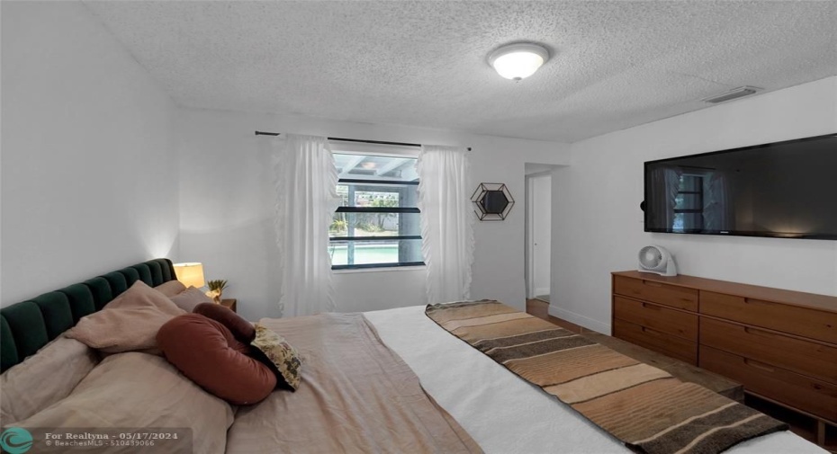 MASTER BEDROOM W/ ENSUITE AND VIEW OF POOL AND EXIT TO SCREENED-IN PATIO.