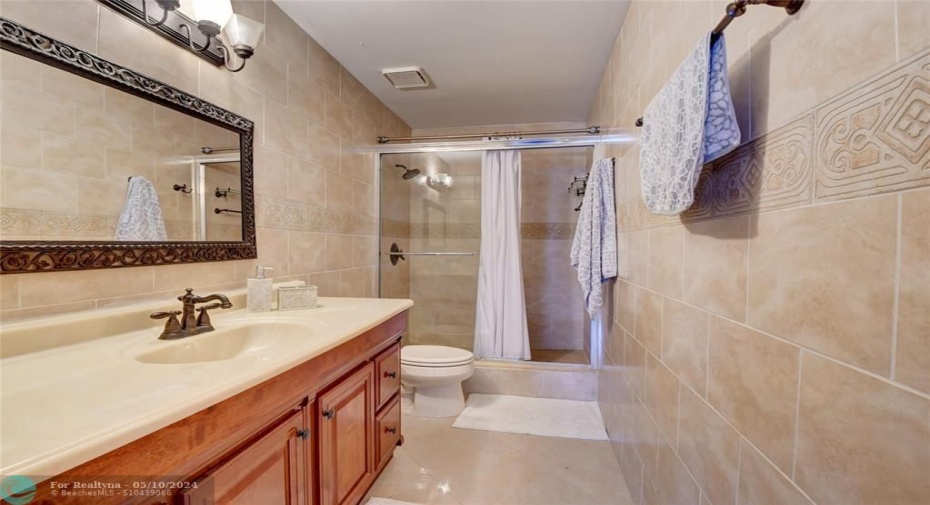 fully tiled master bathroom with linen closet