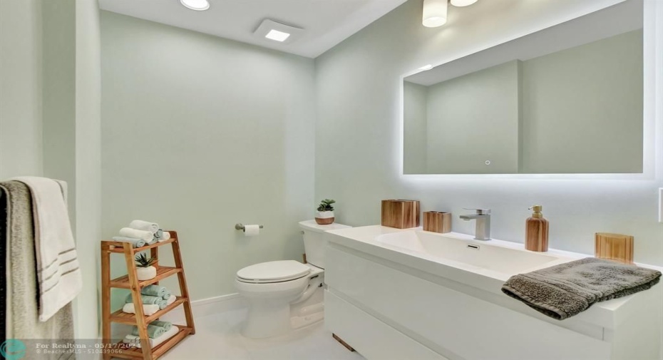 Backlit mirror, modern fixtures & recessed lighting provide a bright clean look.