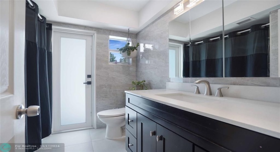 The second bathroom has lovely tiled walls and a quartz vanity.