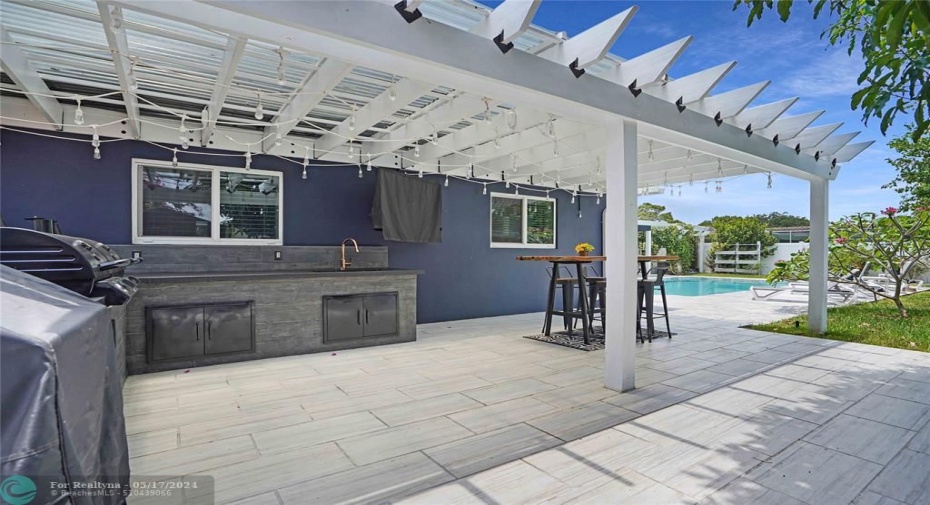 This kitchen has a custom made pergola and a tv.