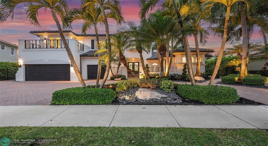 Front view of the Home all lit up at night time with the orange & purple sky (circular driveway)