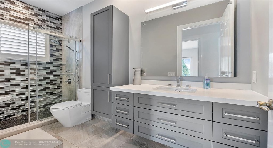 One of the 5 full modern bathrooms with floating vanity, linen closet and state of the art toilet,Full barndoor glass shower with accent wall.
