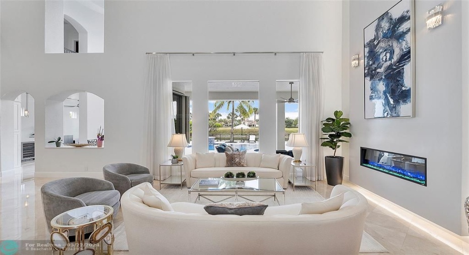 The view as you walk into the home after the circular lobby, Looking out onto the modern sapphire blue patio and pool, The pretty living room window with sheers or without? The floor to ceiling modern fireplace can be changed colors with remote control, most furniture was custom made for this home so could be negotiated but not all!