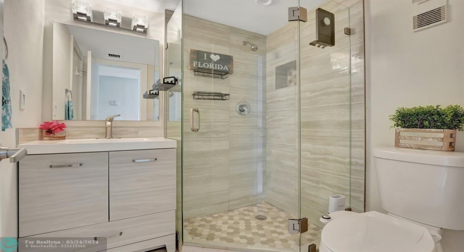 Guest bath updated to perfection! Wash away your worries in the frameless shower with pebble flooring. Pretty lighting too!
